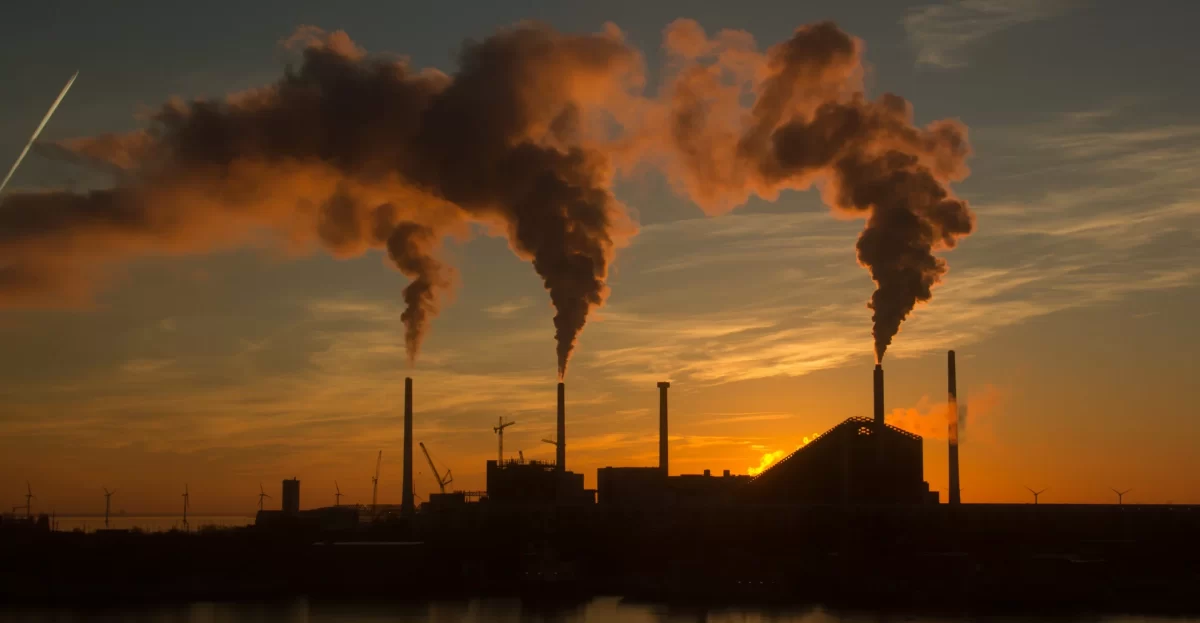 Factory smokestacks emitting smoke at sunset, illustrating carbon accounting questions founders and operators need to answer clearly.